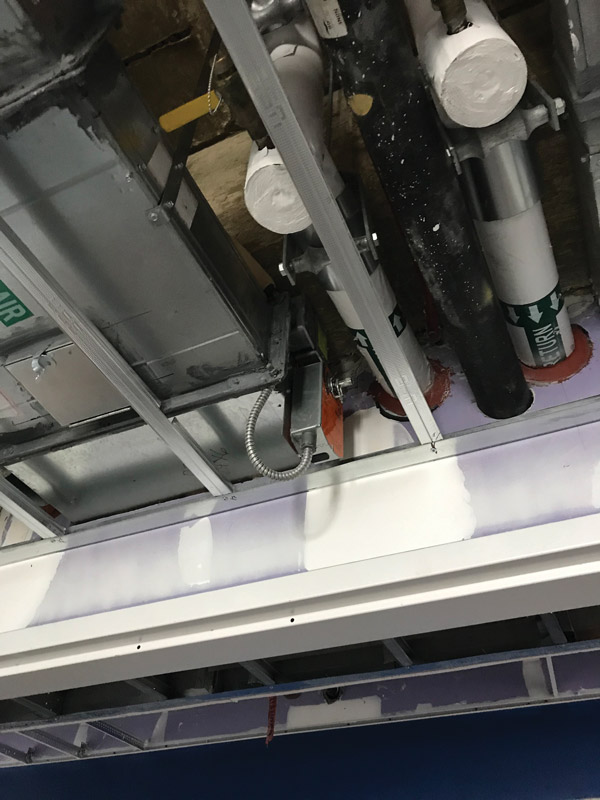 PHOTO A. Smoke damper installed with actuator below the ceiling line. The sleeve was extended and the damper was relocated to clear the ceiling line.